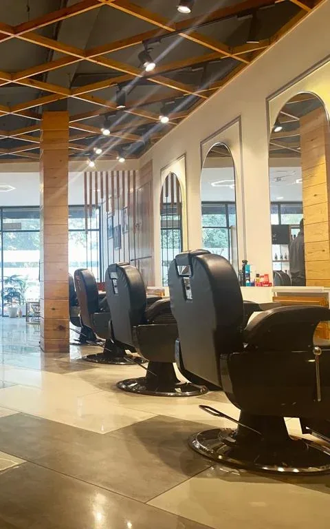 A row of black leather barber chairs at Glamz Unisex Salon beneath the timber lattice ceiling