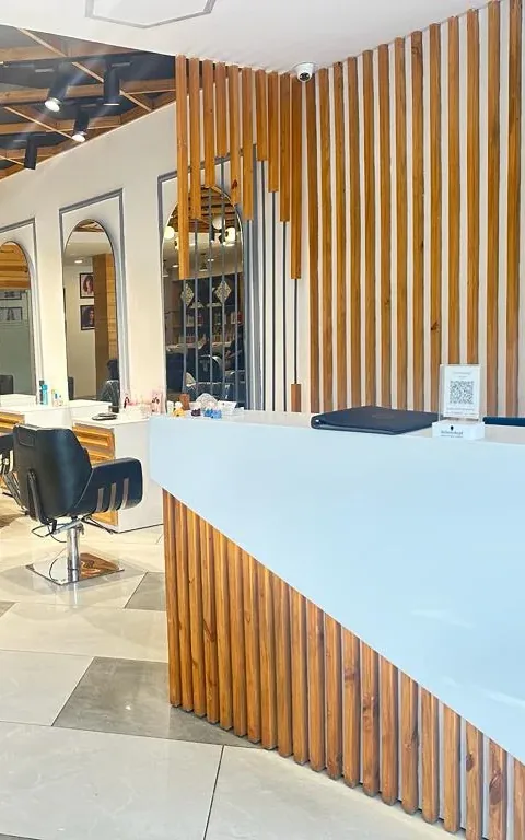 The reception counter at Glamz Unisex Salon, faced in vertical timber battens, with a timber screen behind it